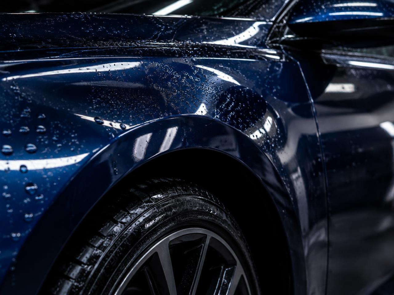 Glossy dark blue fender with water droplets after exterior detailing
